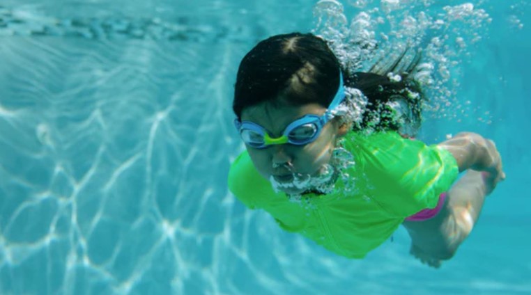 Kid swims in a SwimZip's neon green rash guard—Are green swimsuits safe