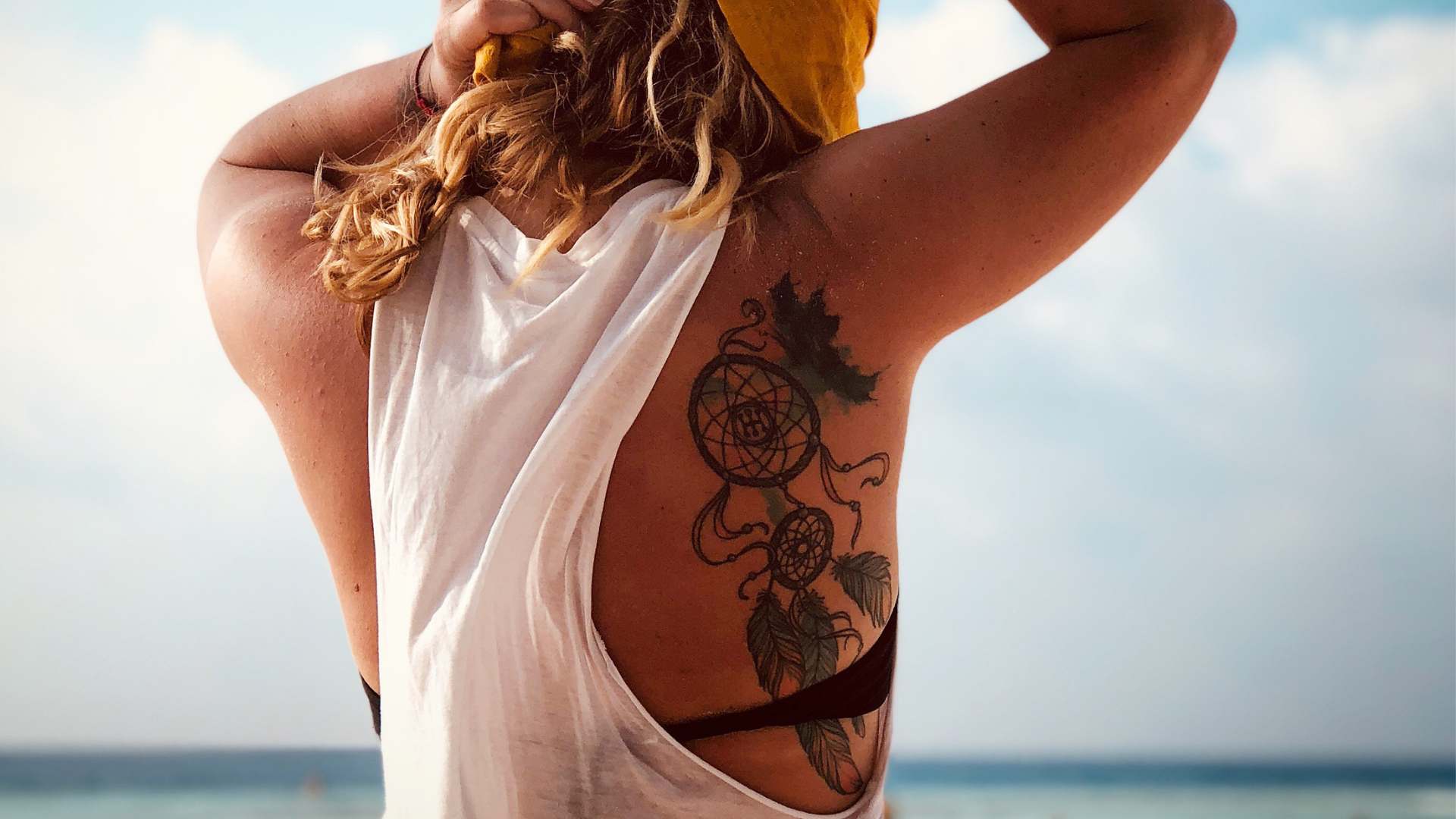 Woman with a tattoo on the beach—How long after a tattoo can you swim