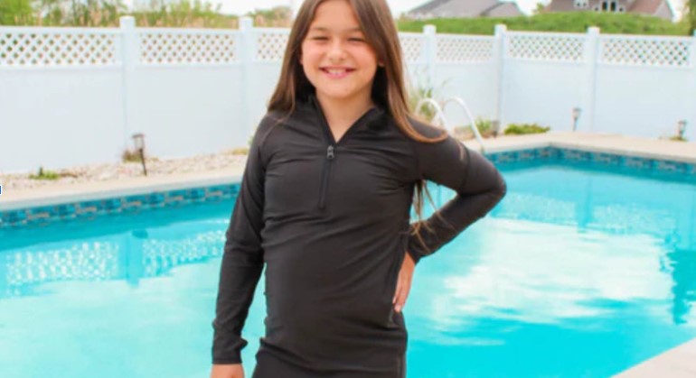 Tween girl in a SwimZip's black swim dress by the pool—How to find modest swimwear for tweens