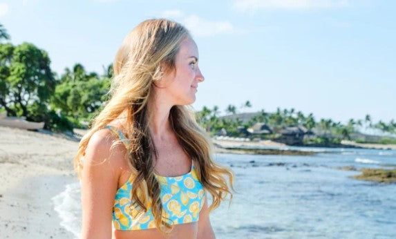 Woman in a SwimZip bikini top walks on a beach—What are the different types of bikini tops?