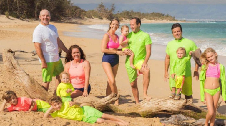 Friends and family in SwimZip neon swimwear collection at the beach — What is the best swimsuit color for safety? by SwimZip