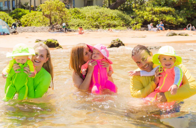 Parents in shallow waters at the beach with babies wearing oversized wide brim hats by SwimZip—How wide should the hat brim be for sun protection?