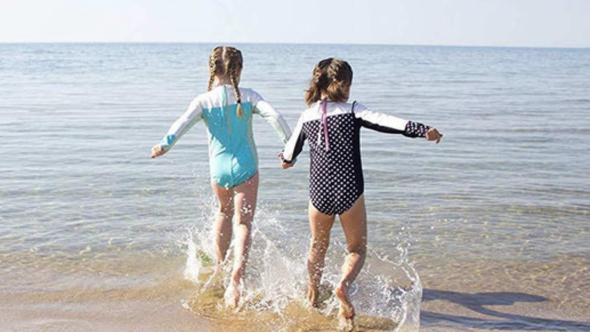 Two girls playing on the beach by the water-8 useful tips to protect your child from drowning