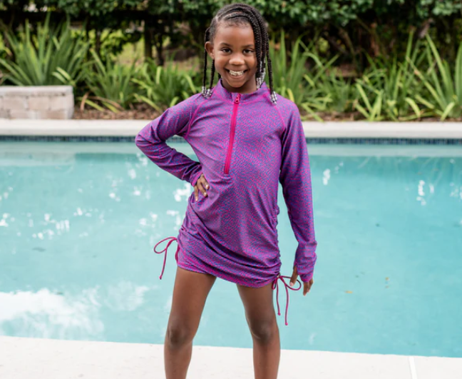 A happy girl wearing SwimZip's swimdress by the pool—How to keep children safe around the pool