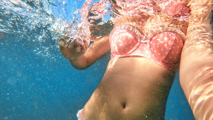 Woman in a two-piece bathing suit swims in a water—How to wash swimsuits.