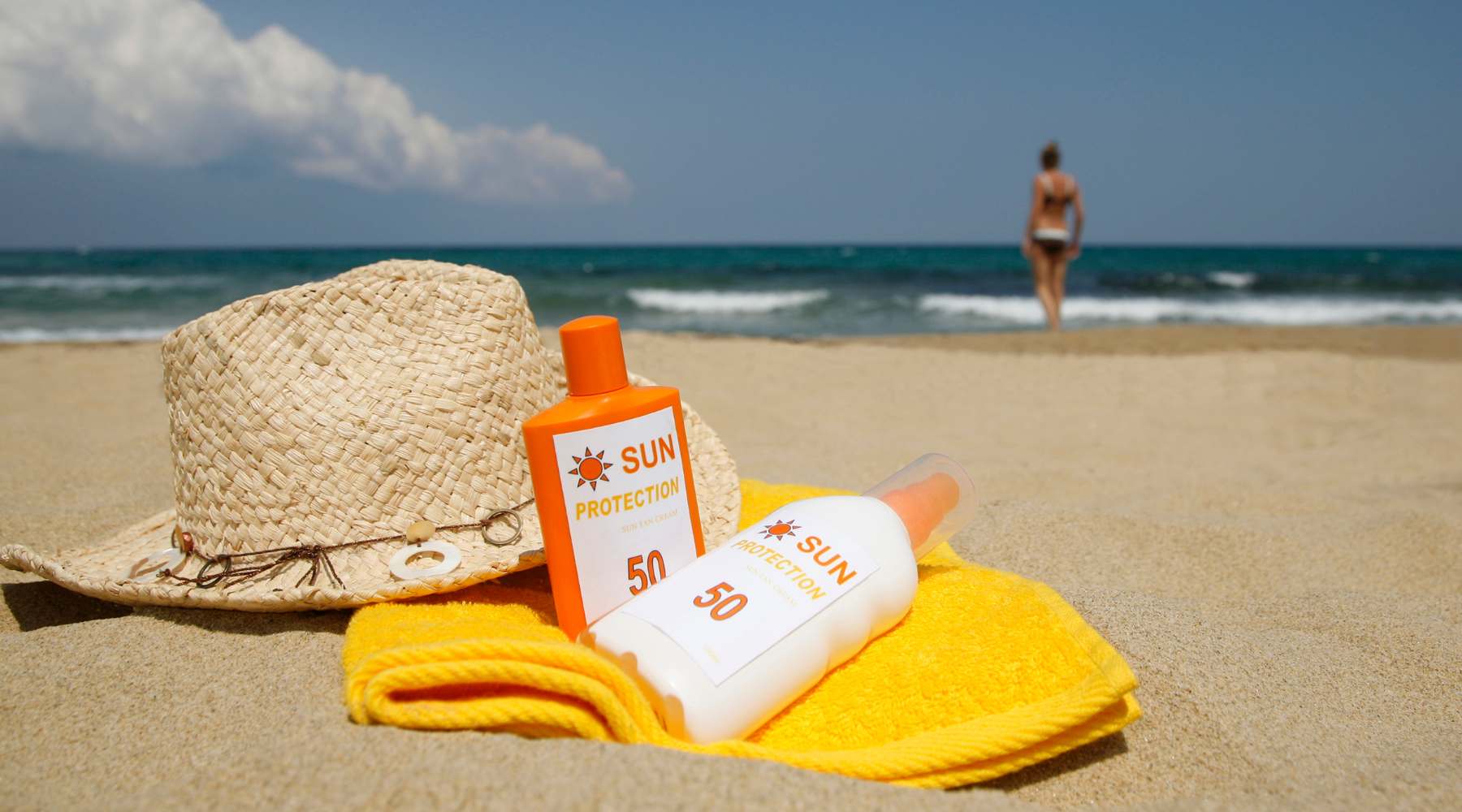 Hat, sunscreen, and a towel at the beach—Sun protection tips