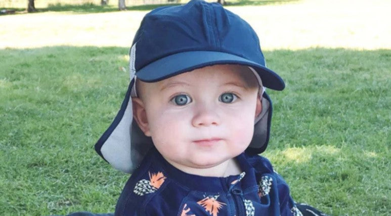 Baby boy with SwimZip sun hat and sunsuit in the shade—Sun safety: Useful tips for kids (and parents)