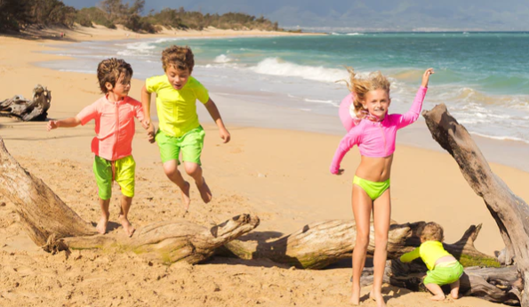 Kids playing on a beach in SwimZip neon swimsuits - Why should kids wear neon bathing suits?