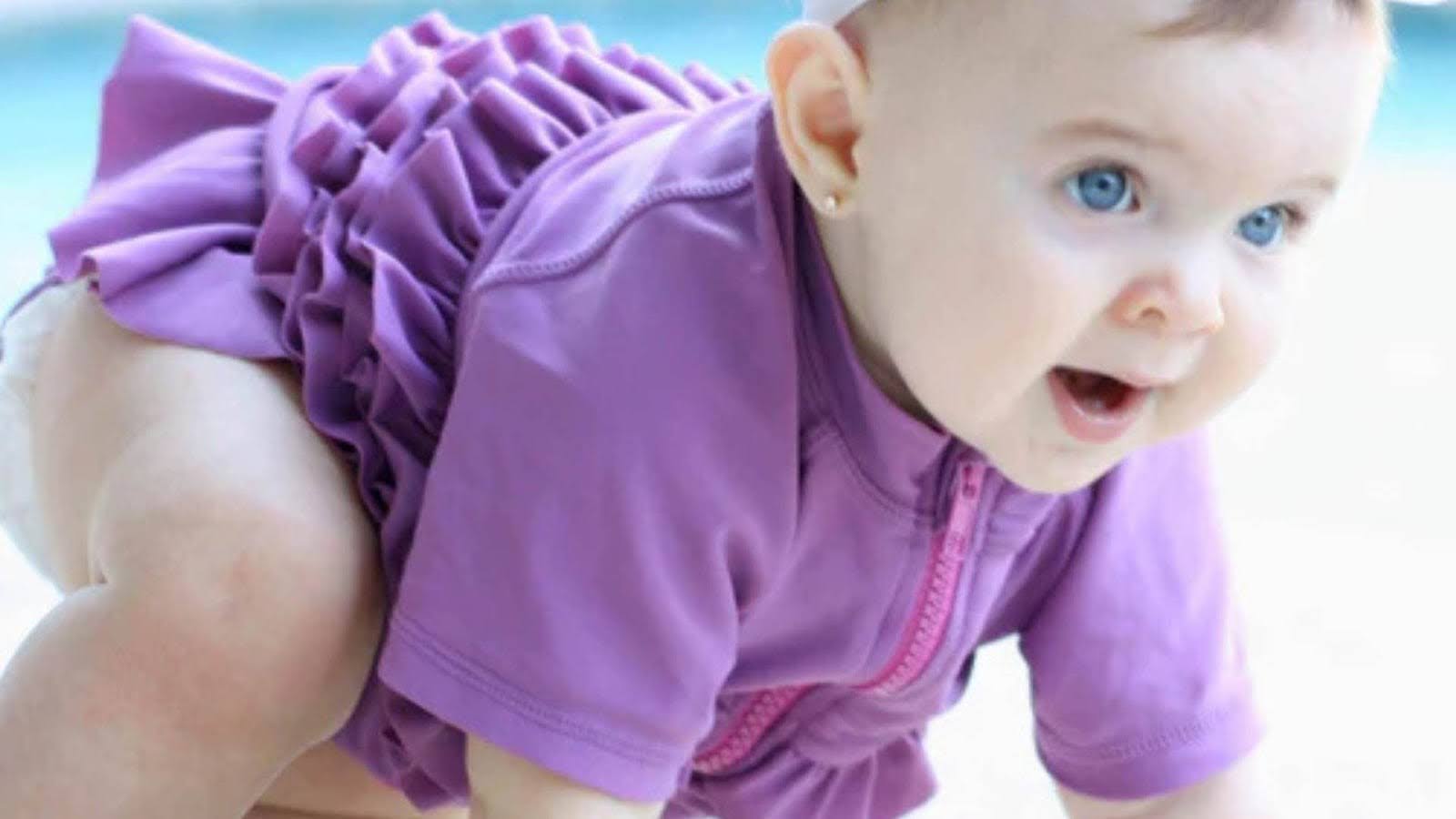 Baby in a SwimZip's purple swimsuit by the pool—Are purple swimsuits safe?